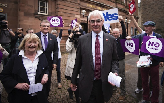 El director de la campaña unionista "Mejor Juntos", el ex Ministro laborista Alistair Darling (centro), y su mujer, Maggie (izda), caminan mientras votantes a favor del "sí" y del "no" permanecen a la entrada de un colegio electoral en Edimburgo en Escocia (Reino Unido). Foto: EFE