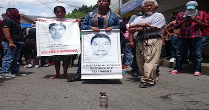 Familiares de los normalistas desaparecidos frente a una bomba lacrimógena arrojada por los policías. Foto: El Sur  