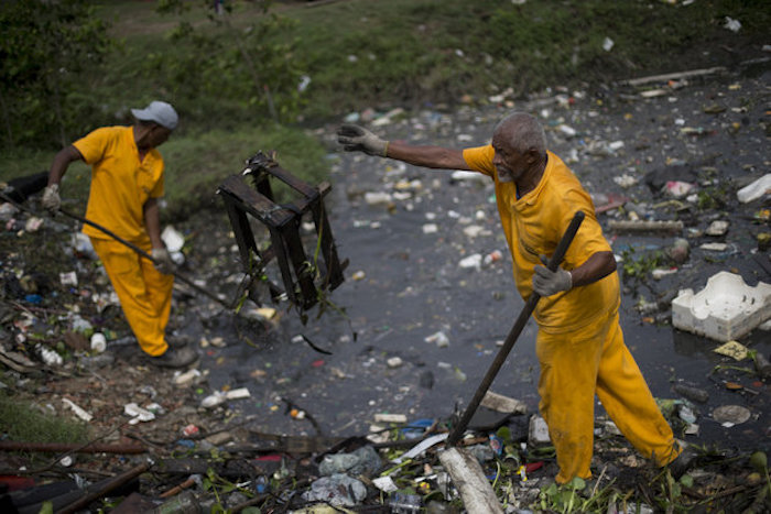 Trabajadores remueven la basura recolectada por barreras flotantes de desechos en el río Meriti, que desemboca en la Bahía de Guanabara, en Río de Janeiro, Brasil. Foto: AP