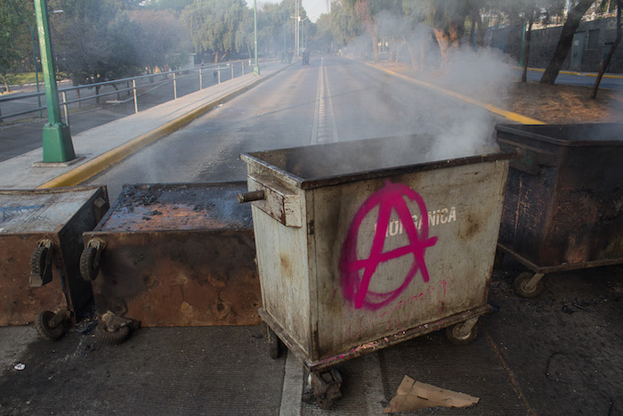 El tránsito para ingresar al circuito escolar en el punto está impedido por una barricada de contenedores de basura, los cuales también fueron quemados. Foto: Cuartoscuro.