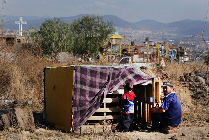 Una pequeña familia reposa después de levantar una pequeña casa de madera en el predio llamado Quinceo, en Morelia, Michoacán. Foto: Cuartoscuro