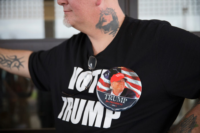 John Drury usa una camiseta y un broche en apoyo a Donald Trump mientras espera a que inicie un acto de campaña del aspirante presidencial republicano en el Savannah Center, en West Chester Township, Ohio, el domingo 13 de marzo de 2016. Foto: John Minchillo, AP