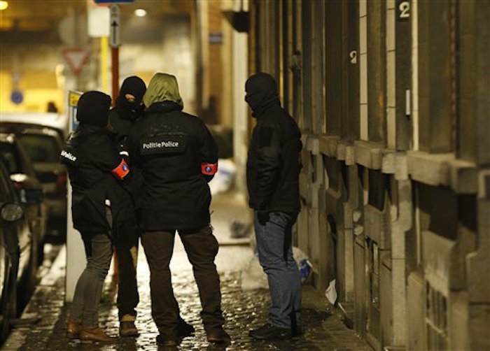 PolicÌas vigilan la parte exterior de una casa registrada por la policÌa en el suburbio de Schaerbeek, en Bruselas, el viernes 25 de marzo de 2016. (AP Foto/Alastair Grant)