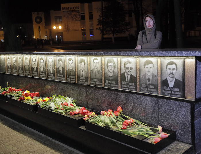 Una mujer, de pie junto a un monumento que recuerda a los trabajadores y bomberos de la central nuclear de Chernobyl. Foto: AP.