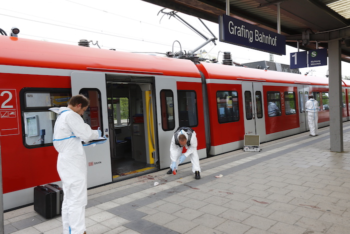 Dos investigadores analizan la zona donde se produjo una agresión con arma blanca en una estación de tren en Grafing, cerca de Múnich, en Alemania. Foto: AP. 