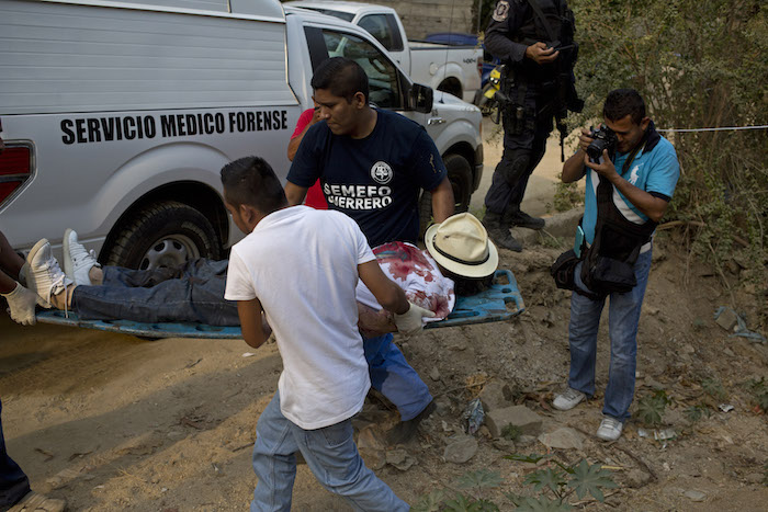 Trabajadores forenses retiran el cadáver de un hombre baleado cuatro veces en un lote baldío entre zonas residenciales en la colonia Leyes de Reforma. Foto: AP