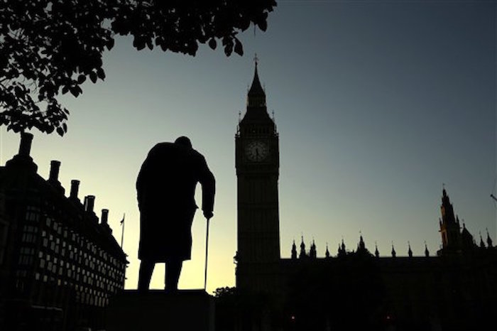 La silueta de una estatua de Winston Churchill resalta junto a las de los edificios del Parlamento en Londres, al amanecer del viernes 24 de junio de 2016. (AP Foto/Matt Dunham)