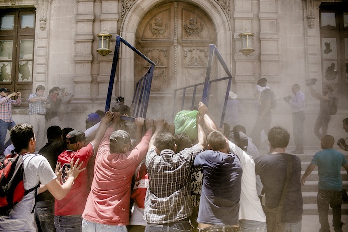 Manifestantes golpeando la puerta del Palacio de Gobierno de Chihuahua. Foto: Cuartoscuro. 