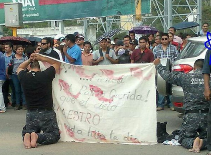 Una vez hincados fueron obligados a portar una manta, la cual contenía las exigencias de la CNTE en contra de la reforma educativa. Foto: NSSOaxaca