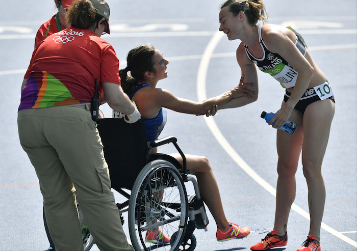 La neozelandesa Nikki Hamblin saluda a la estadounidense Abbey D'Agostino cuando es sacada de la pista en una silla de ruedas. Foto: AP