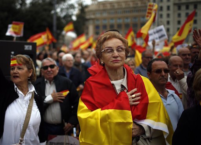 Un grupo de personas escucha el himno nacional durante una celebraciÛn del DÌa Nacional en España. Foto: AP/Manu Fernández.