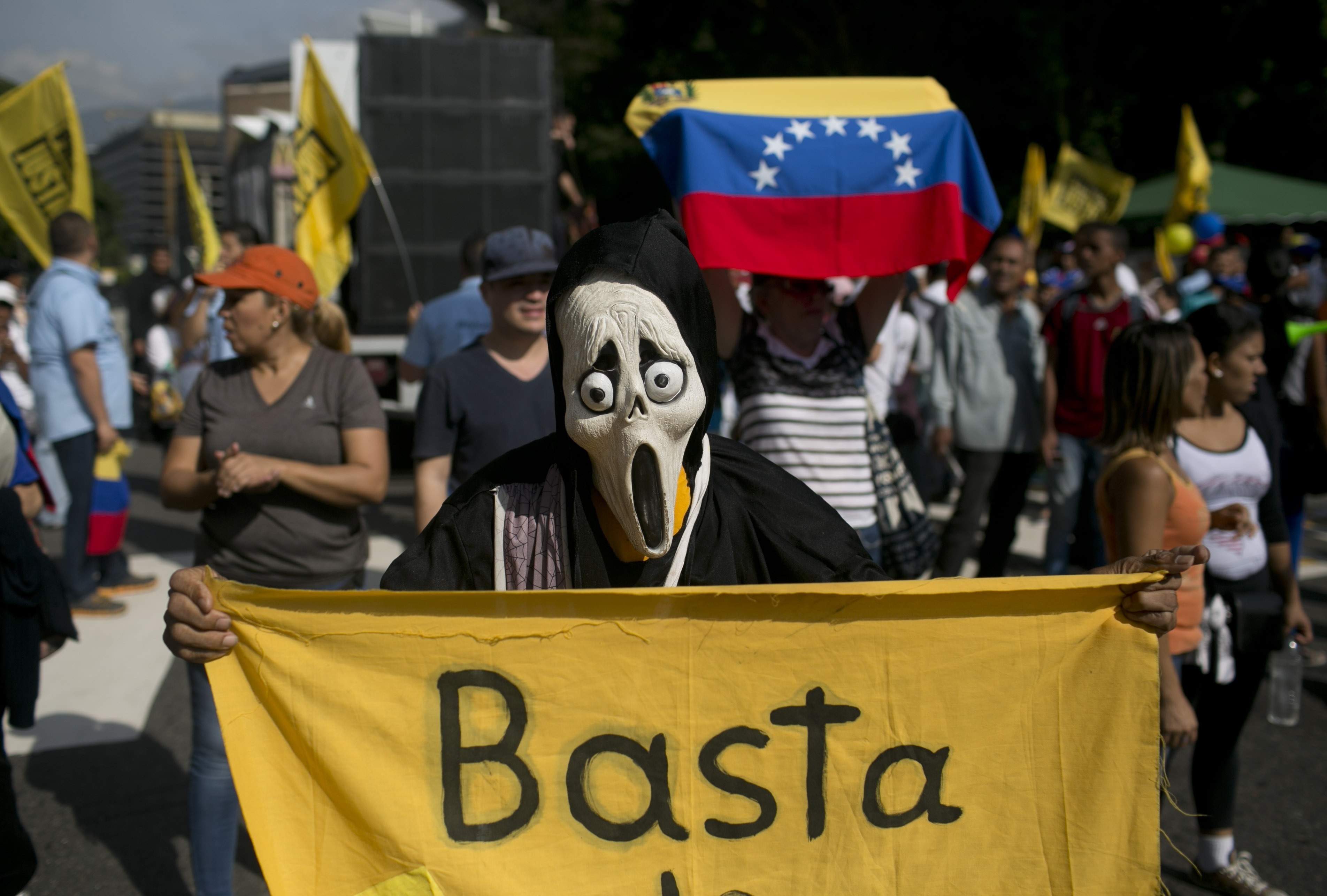 Un manifestante enmascarado sostiene un cartel que dice Basta y rinde protesta contra el presidente Nicolás Maduro en Caracas, Venezuela. Foto: AP