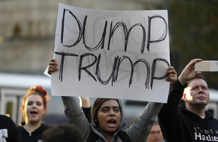 Una manifestante sostiene un letrero con la leyenda "Fuera Trump" mientras participa en una protesta en contra del presidente electo Donald Trump el miércoles en el centro de Seattle. Foto: AP