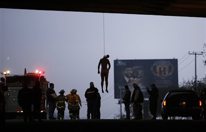 En esta fotografía de archivo del 9 de octubre de 2009, el cad·ver de un hombre cuelga del cuello bajo un puente en la antigua carretera de Rosarito, en Tijuana, Baja California, en MÈxico. La vÌctima no fue identificada y su cuerpo presentaba seÒales de tortura como golpes y mutilaciones. La violencia ha bajado un poco desde que los homicidios alcanzaron niveles horripilantes en los diez aÒos que ha durado la guerra contra el narcotr·fico en MÈxico. Los descubrimientos de fosas clandestinas y pilas de cad·veres ya no suceden con la frecuencia de antes, pero persisten las balaceras. (AP Foto/Guillermo Arias, Archivo)