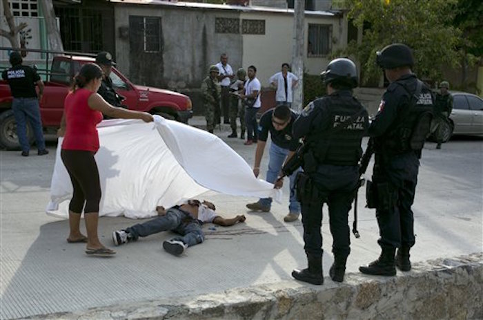 ARCHIVO - En esta fotografÌa de archivo del 15 de abril de 2016, un mÈdico forense ayuda a una mujer a cubrir con una s·bana el cad·ver de Alejandro Gallardo PÈrez, de 23 aÒos, quien fue asesinado a tiros cerca de su casa en San AgustÌn, en las afueras de Acapulco. Diez aÒos despuÈs de que MÈxico declarara la guerra a los carteles del narcotr·fico, esta ofensiva ha contribuido muy poco para reducir la violencia y la delincuencia en las regiones m·s hostiles del paÌs. (AP Foto/Enric Marti, Archivo)