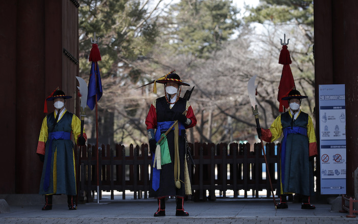 Guardias con uniformes tradicionales y mascarillas ante la entrada del palacio Deoksu en el centro de Seúl, Corea del Sur, el domingo 23 de febrero de 2020. Foto: Lee Jin-man, AP