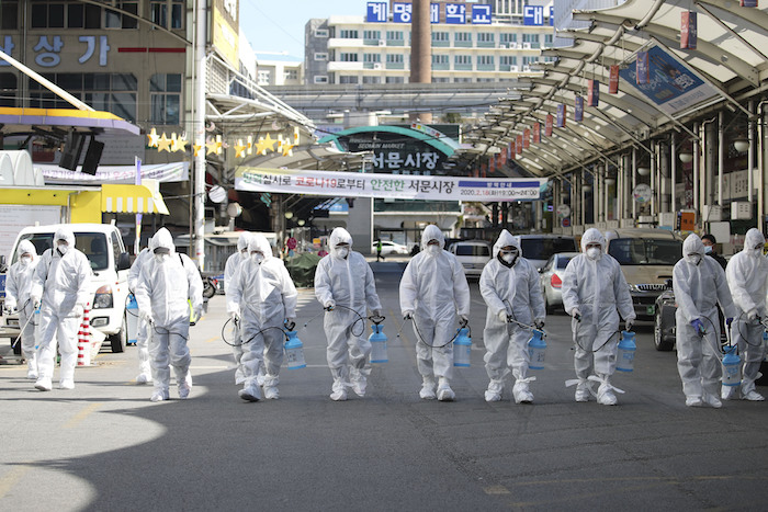 Trabajadores en trajes protectores rocían desinfectante para prevenir contagios con el coronavirus que produce la enfermedad COVID-19, en un mercado local de Daegu, Corea del Sur, el domingo 23 de febrero de 2020. Foto: Im Hwa-young/Yonhap vía AP