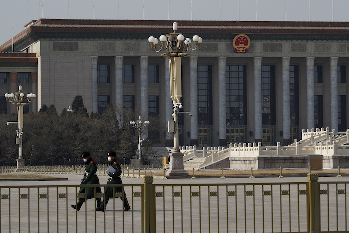 En esta imagen del domingo 23 de febrero de 2020, policías paramilitares con mascarillas de protección caminan por la vacía plaza de Tiananmen, con el Gran Salón del Pueblo al fondo, en Beijing, China. Foto: Andy Wong, AP