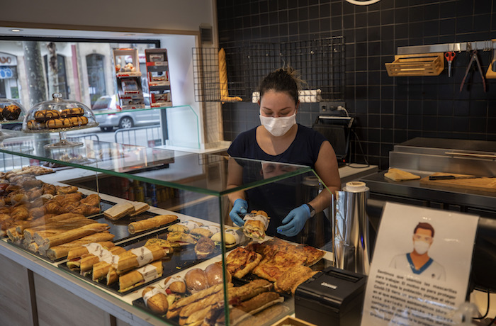 Una mujer con mascarilla prepara sandwiches en Barcelona el sábado 14 de marzo de 2020. Foto: Emilio Morenatti, AP