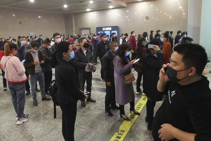 Viajeros hacen fila para comprar boletos de tren en Yichang, provincia de Hubei, China, miércoles 25 de marzo de 2020. Foto: Chinatopix vía AP