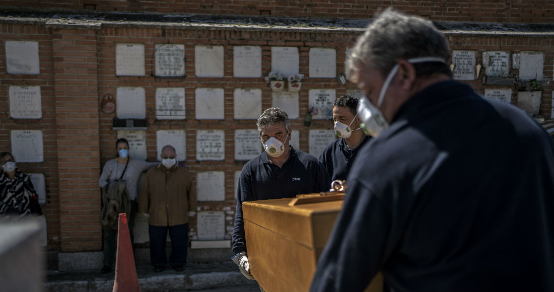 En el centro a la izquierda, la hija y el esposo de una anciana fallecida por COVID-19, de pie mientras los enterradores colocan el ataúd en su tumba en el cementerio de La Almudena en Madrid, España, el sábado 28 de marzo de 2020. Los nombres de las personas en la imagen no estaban disponibles. Foto: Olmo Calvo, AP