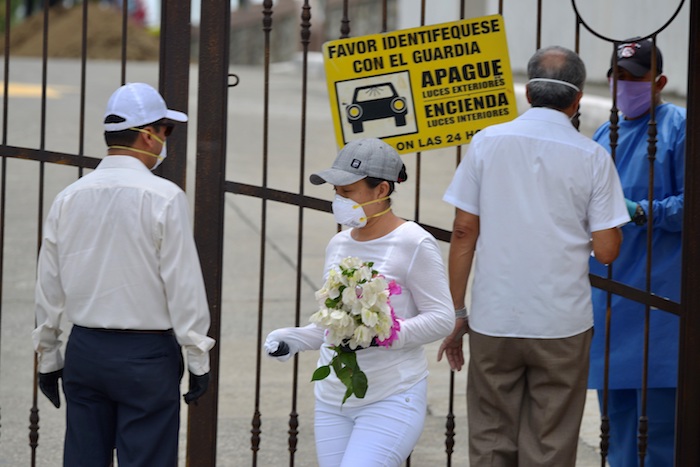 Familiares con tapabocas hacen consultas este miércoles a un guardia de seguridad de un cementerio, para poder despedir a sus seres queridos, en Guayaquil (Ecuador). Foto: Marcos Pin, EFE