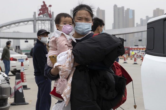 En esta imagen, tomada el 2 de abril de 2020, una mujer con una niña en brazos se aleja de una carretera en la frontera de la ciudad de Wuhan, en la provincia de Hubei, en el centro de China. Foto: Ng Han Guan, AP