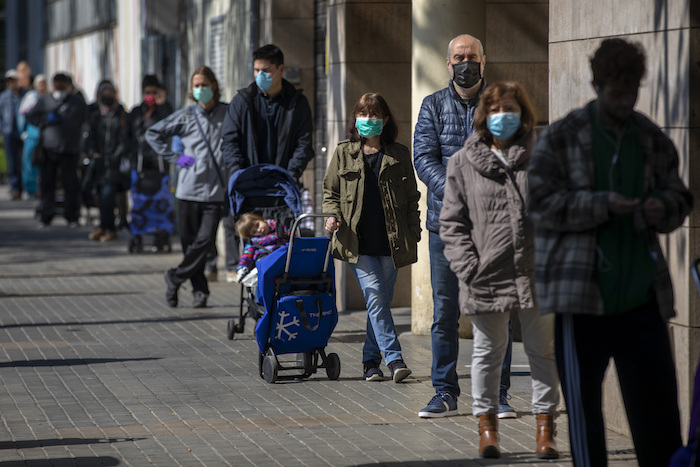 Personas con mascarillas se forman para comprar provisiones en una tienda durante el brote del coronavirus en Barcelona, España, el sábado 4 de abril de 2020. Foto: Emilio Morenatti, AP