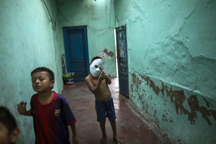 En esta imagen del 24 de marzo de 2020, varios niños, uno de ellos con una máscara de Jason de Halloween, juegan en la casona ruinosa apodada "Luriganchito" por la prisión más populosa del país, en Lima, Perú.