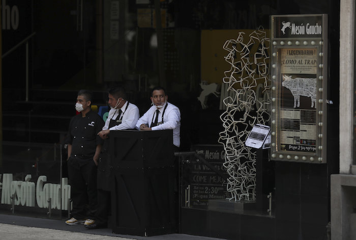 Meseros de un restaurante que sólo tiene servicio de comida para llevar, esperan por clientes en la Ciudad de México, el lunes 6 de abril de 2020. 