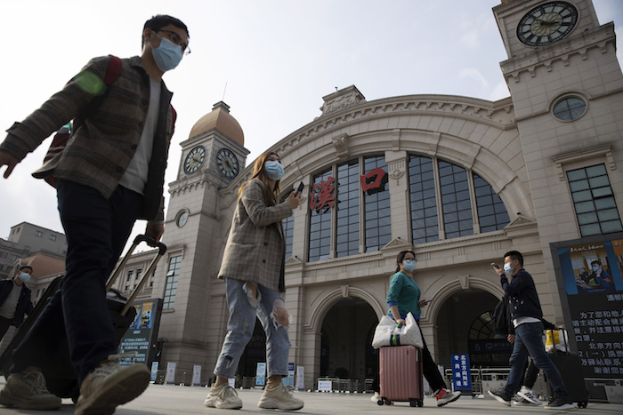 Viajeros con maletas caminan frente a la estación ferroviaria de Hankou cuando se apresta a reanudar el tráfico desde Wuhan, China, hacia afuera de la ciudad, martes 7 de abril de 2020. Foto: Ng Han Guan, AP