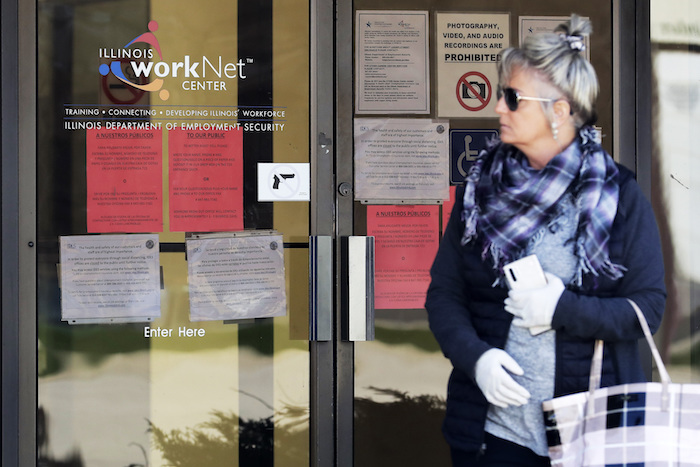 Una mujer lee información sobre solicitudes de empleo frente al Departamento de Seguridad Laboral de Illinois en el centro WorkNet en Arlington, Heights, Illinois, el jueves 9 de abril de 2020. 