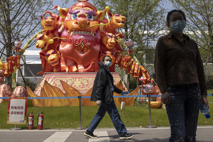 Residentes utilizan mascarillas para protegerse del coronavirus mientras caminan frente a esculturas en un parque de Wuhan, en la provincia de Hubei, en el centro de China, el jueves 9 de abril de 2020. 