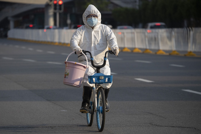 Un residente con mascarilla y traje protector contra el coronavirus, en una bicicleta en la ciudad de Wuhan, en la provincia de Hubei, en el centro de China, el domingo 12 de abril de 2020.