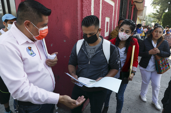 Un trabajador revisa los documentos de un hombre que solicita un trabajo médico fuera del sindicato nacional de trabajadores de la salud en la Ciudad de México, el martes 14 de abril de 2020.