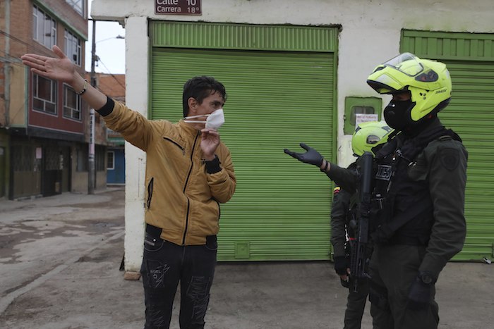 Un policía le pide a un residente su identificación personal durante un toque de queda ordenado por el Alcalde de la ciudad en un esfuerzo por evitar la propagación del nuevo coronavirus, en Soacha, Colombia, el viernes 17 de abril de 2020. Esta zona --en su mayoría de familias de clase trabajadora-- es una de las más afectadas en el país con casos de COVID-19, pero muchos residentes no han respetado una cuarentena ordenada por el Gobierno.