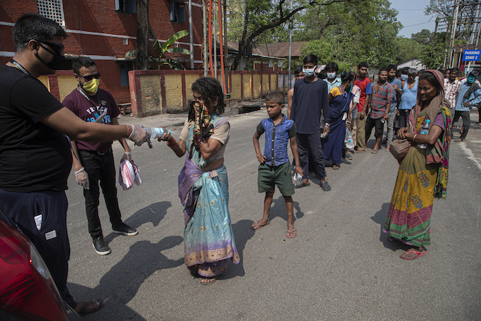 Un grupo de indios reparte comida y agua entre personas sin hogar durante una cuarentena nacional para combatir la expansión del nuevo coronavirus en Gauhati, India, el domingo 19 de abril de 2020. 