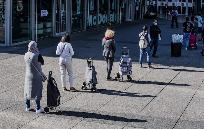 Personas usando cubrebocas hacen fila afuera de una tienda para comprar comida en La Defense, un distrito en París, Francia, en los días de la contingencia por la cuarentena.