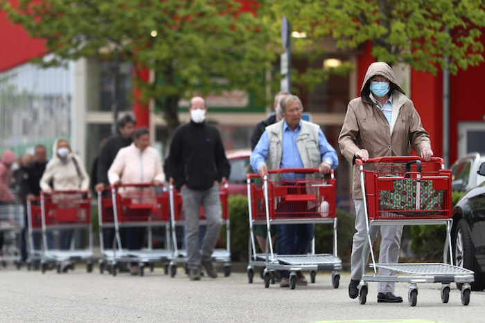 Una fila de personas con mascarillas esperando a entrar a una tienda en Munich, Alemania, el 20 de abril del 2020.