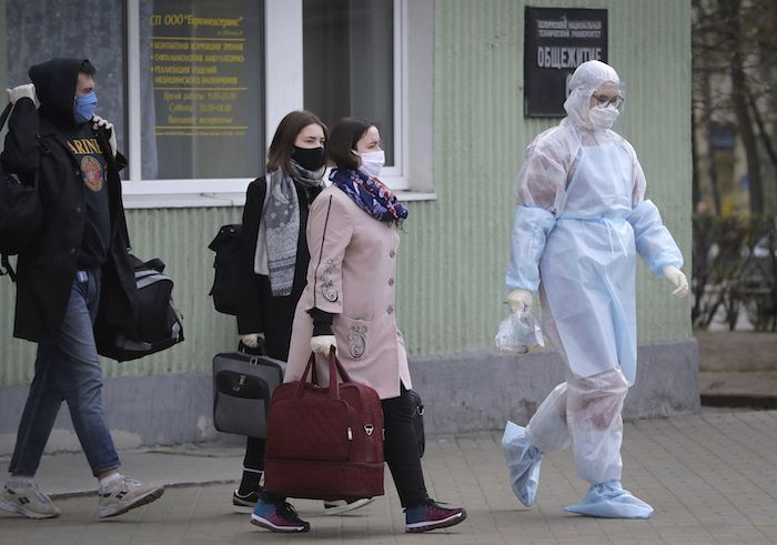 Una trabajadora sanitaria con un traje de protección acompaña a estudiantes hasta una ambulancia, en Minsk, Bielorrusia, el 21 de abril de 2020.