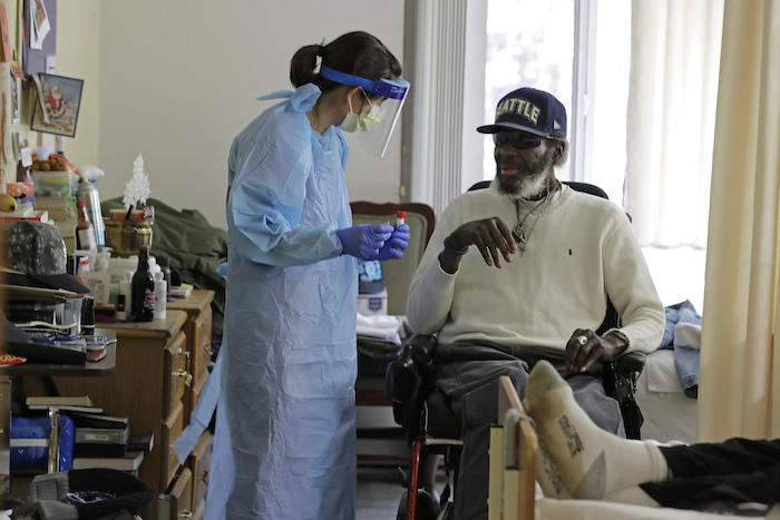 Fotografía del 17 de abril de 2020 de la doctora Gabrielle Beger preparándose para tomar una muestra nasal de Lawrence McGee como parte del equipo de médicos de la Universidad de Washington que realiza pruebas para el nuevo coronavirus en el albergue de ancianos Queen Anne Healthcare en Seattle.