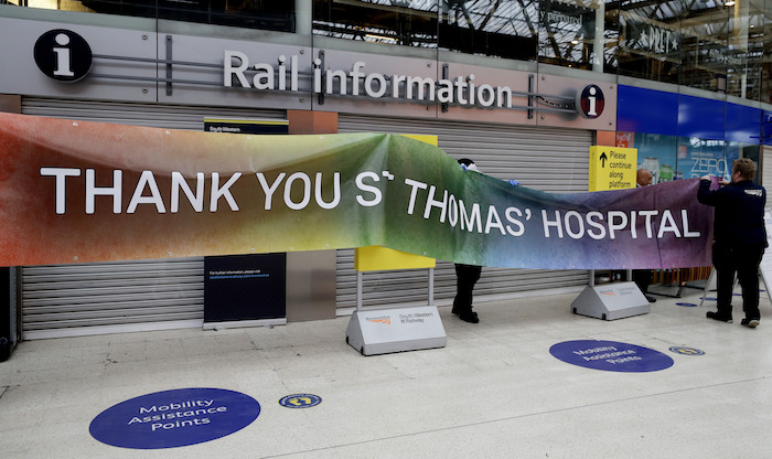 Personal de la estación ferroviaria Waterloo en Londres instala un cartel de agradecimiento al vecino hospital St. Thomas, Londres, martes 18 de abril de 2020.