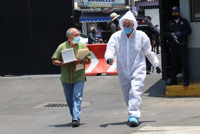 El familiar de una persona que murió con diagnóstico de posible COVID-19 y personal de una funeraria ingresan al Velatorio San Nicolás Tolentino.