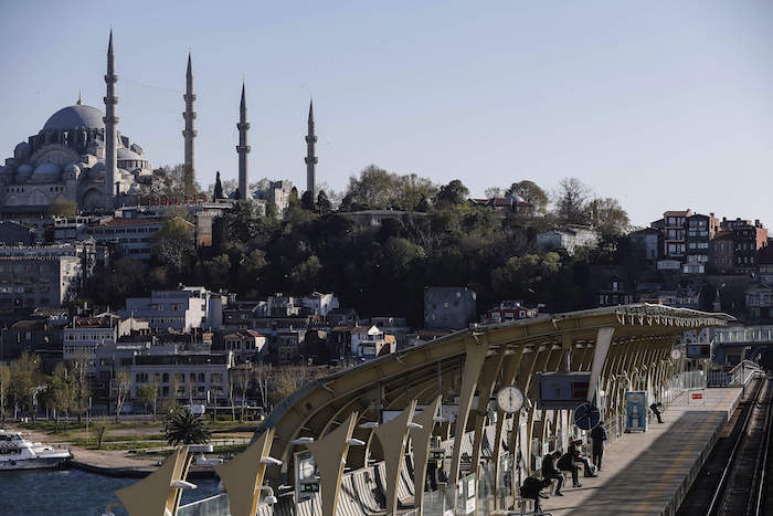 Con la emblemática mezquita de Solimán de fondo, pasajeros esperando en una estación de metro sobre un puente en Estambul, a las 18:00 del viernes 24 de abril de 2020. 