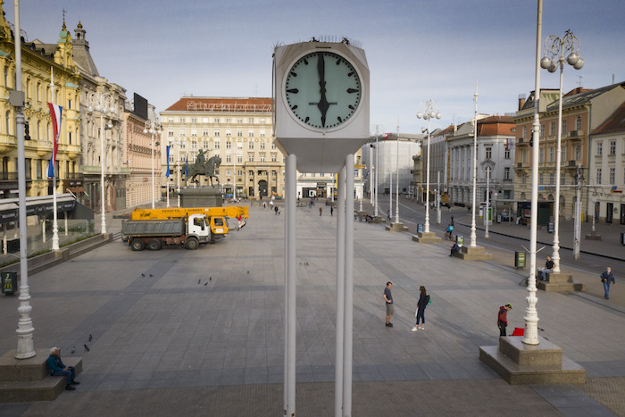 Una vista del reloj y la plaza principal de Zagreb, casi vacía por la cuarentena del coronavirus, a las 18:00 del viernes 24 de abril de 2020. En la plaza se ve maquinaria empleada para reconstrucción tras el reciente sismo en la ciudad. 