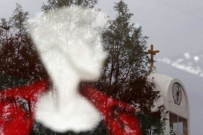 Un reloj situado en la iglesia ortodoxa griega de San Demetrio, visto en el reflejo del escaparate de una tienda de moda, en la capital de Chipre, Nicosia, a las 18:00 del viernes 24 de abril de 2020. 