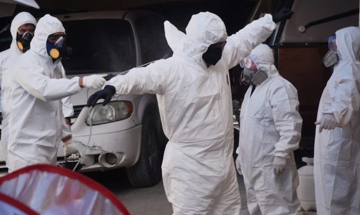 El personal que tiene contacto con los cadáveres sanitiza sus trajes de protección. Foto: Rey R. Jauregui, La Verdad de Juárez