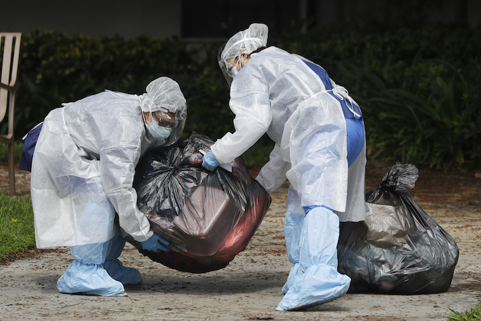 Fotografía de archivo del 8 de abril de 2020 de empleados poniendo pertenencias personales de un paciente que es desalojado del Centro de Rehabilitación y Cuidado Magnolia en Riverside, California.