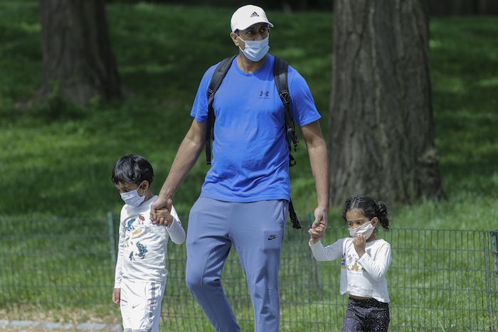 Un hombre y sus hijos, todos con mascarillas para protegerse del coronavirus, pasean en Central Park, Nueva York, el sábado 16 de mayo de 2020.