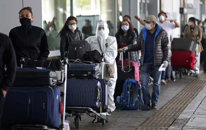 Pasajeros hacen fila para un vuelo humanitario a Italia el lunes 18 de mayo de 2020 usando mascarillas para protegerse del coronavirus, una pandemia que ha ocasionado la cancelación de vuelos nacionales e internacionales en el aeropuerto El Dorado en Bogotá, Colombia. 